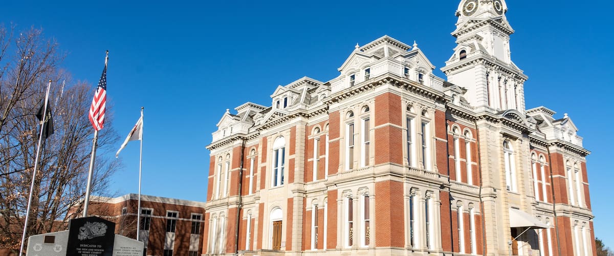 A large, historic building with a prominent clock tower and a flagpole with the American flag.