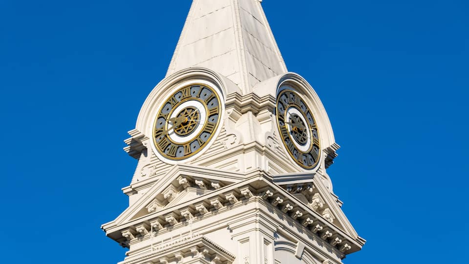A clock tower with two large circular clocks and intricate architectural details against a clear blue sky.