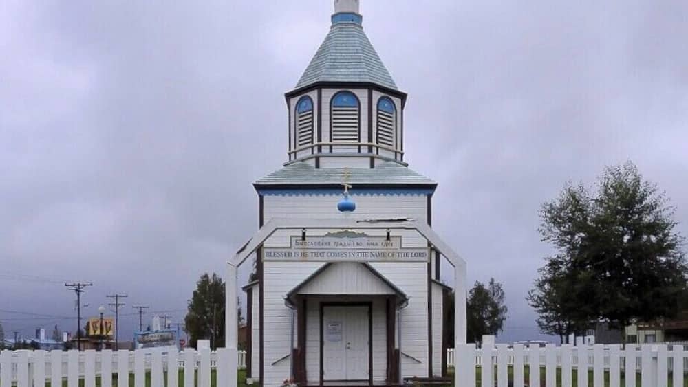 A church with a blue dome and a white fence surrounding it.