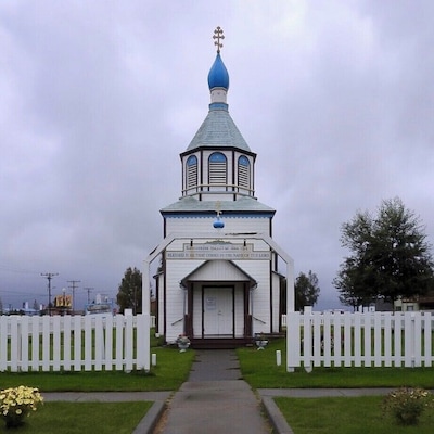 Eine Kirche mit einer blauen Kuppel und einem weißen Zaun darum.