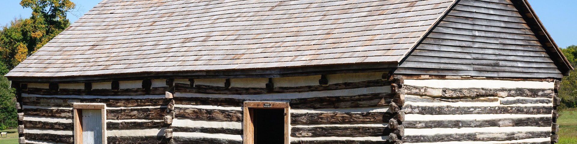 Una cabaña de troncos con techo pronunciado y chimenea.
