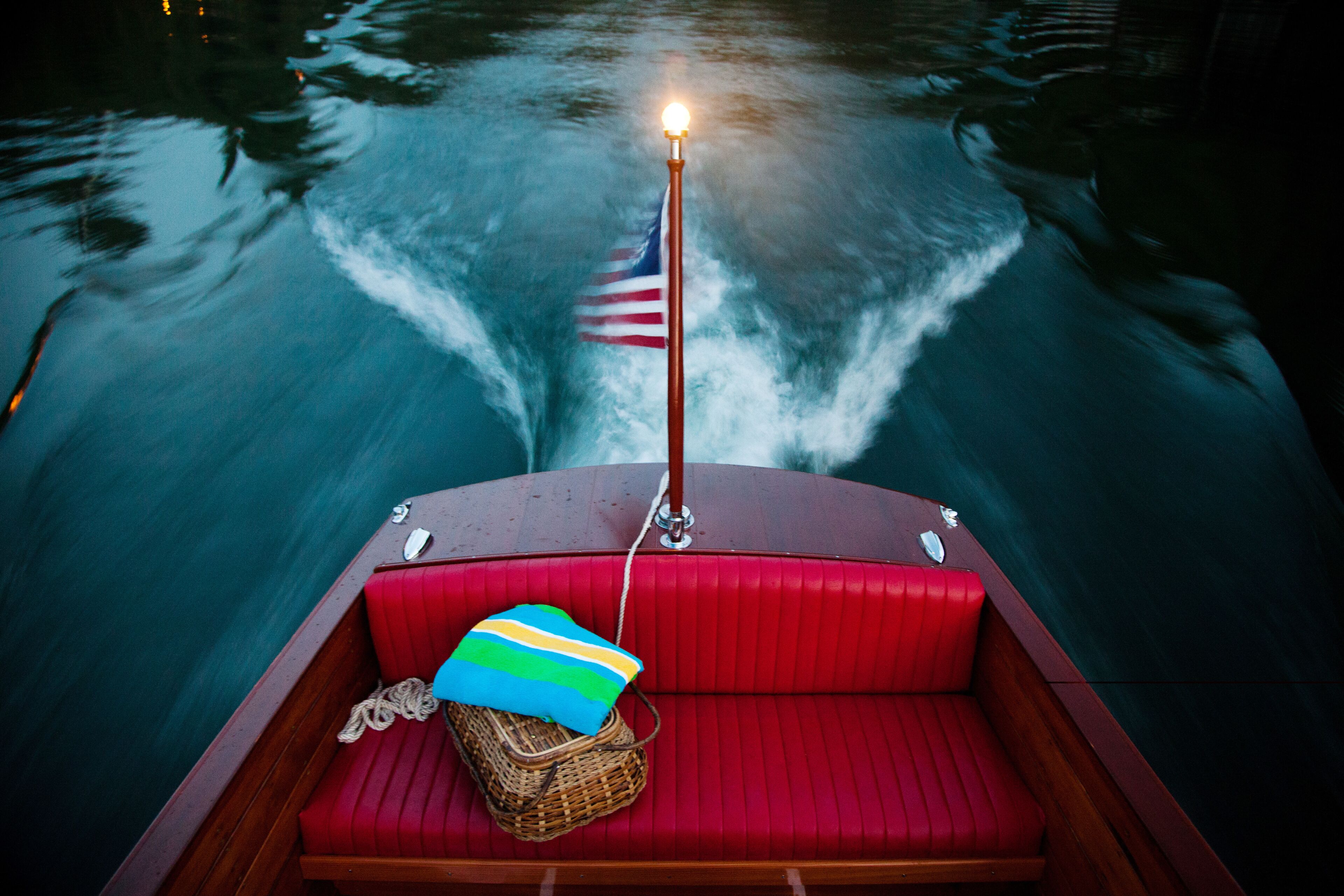 The empty back bench of an antique wooden boat after sunset on a southern lake.