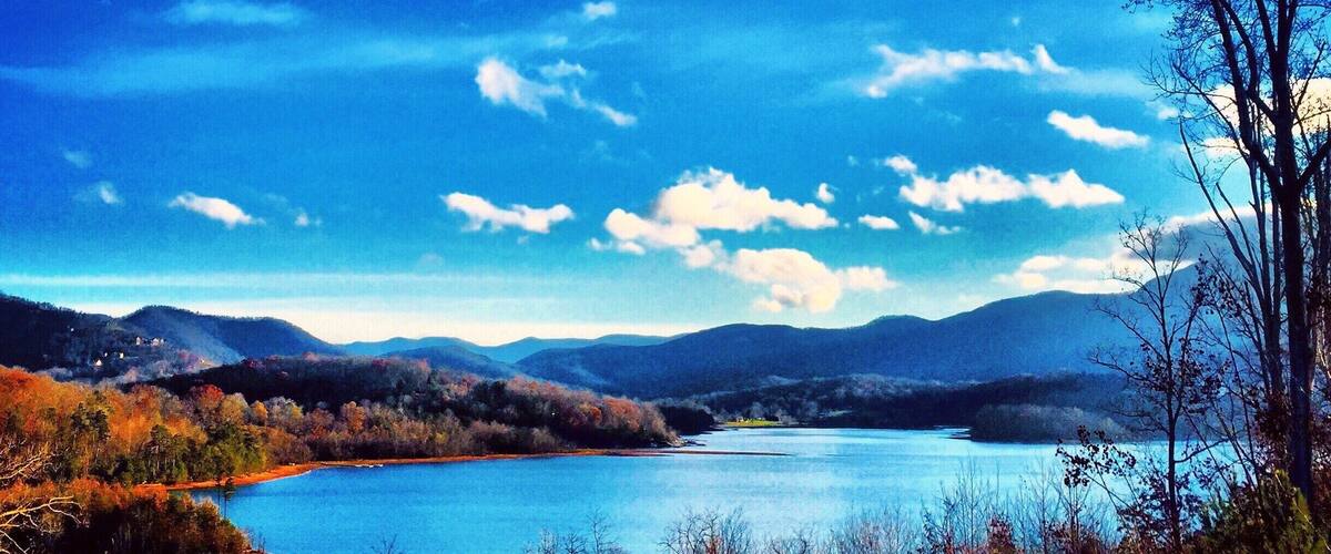 Un lago rodeado de montañas y árboles de colores otoñales.