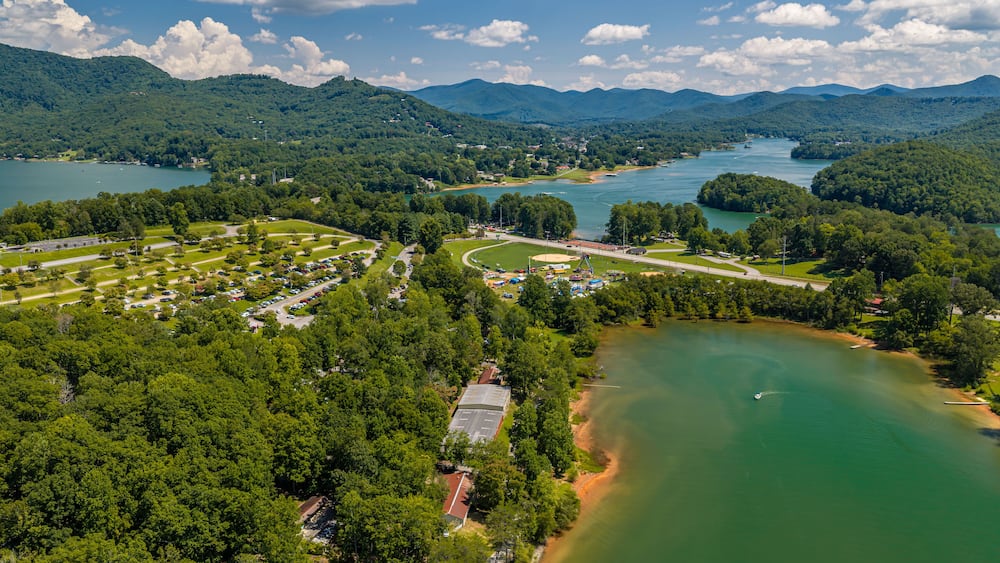 A lake surrounded by mountains, a parking lot, and a baseball field.