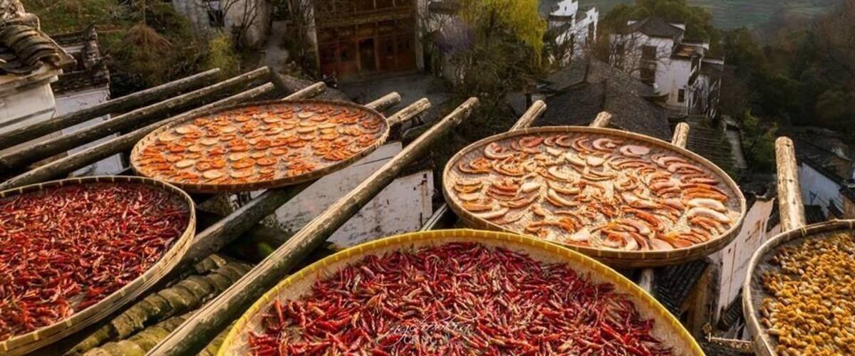 A traditional market with dried seafood displayed on wooden trays.