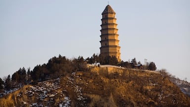 Una pagoda alta sobre una colina con parches de nieve.