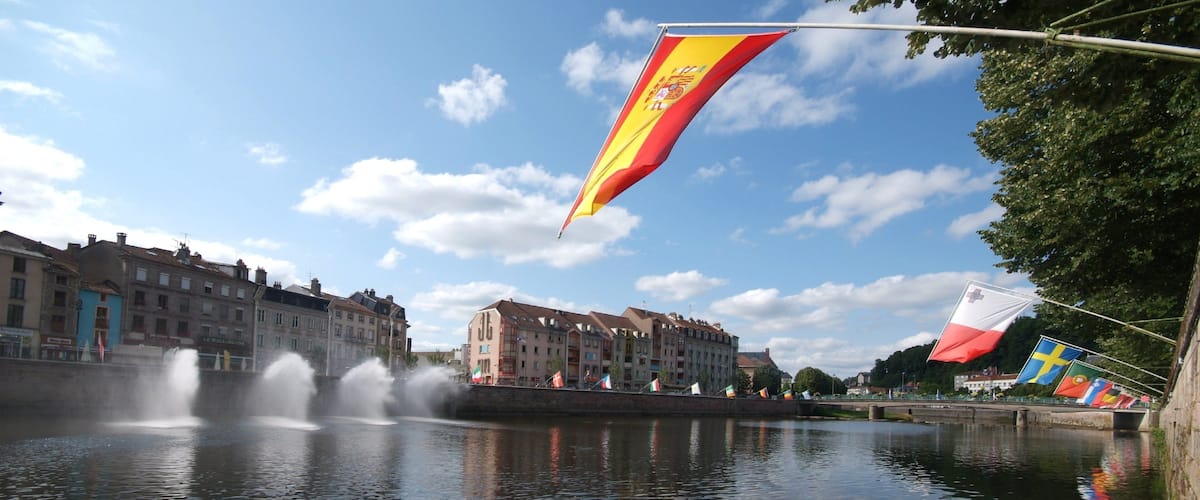 A river with fountains, buildings, and flags.