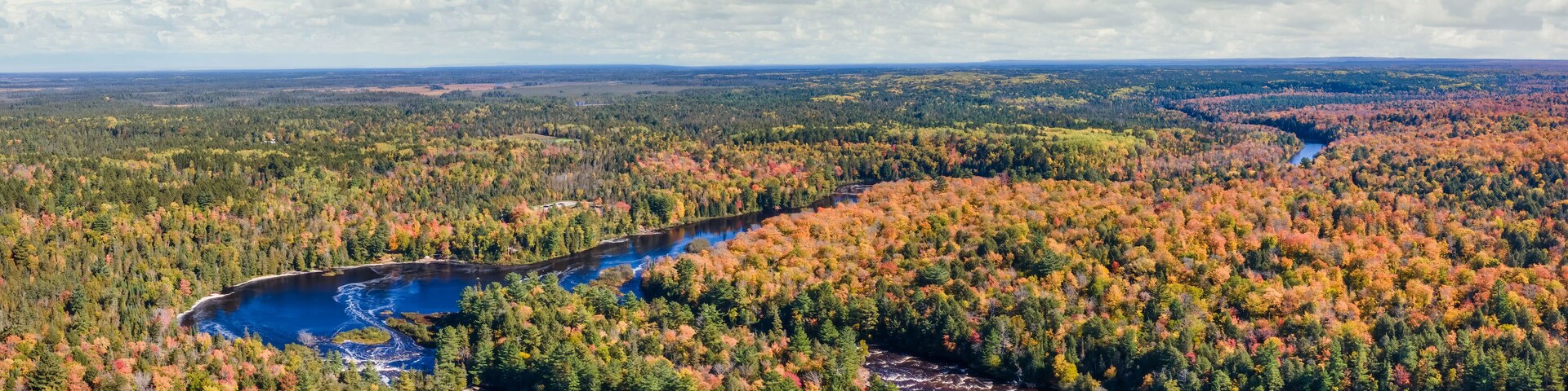 Un río serpentea por un bosque de follaje otoñal.