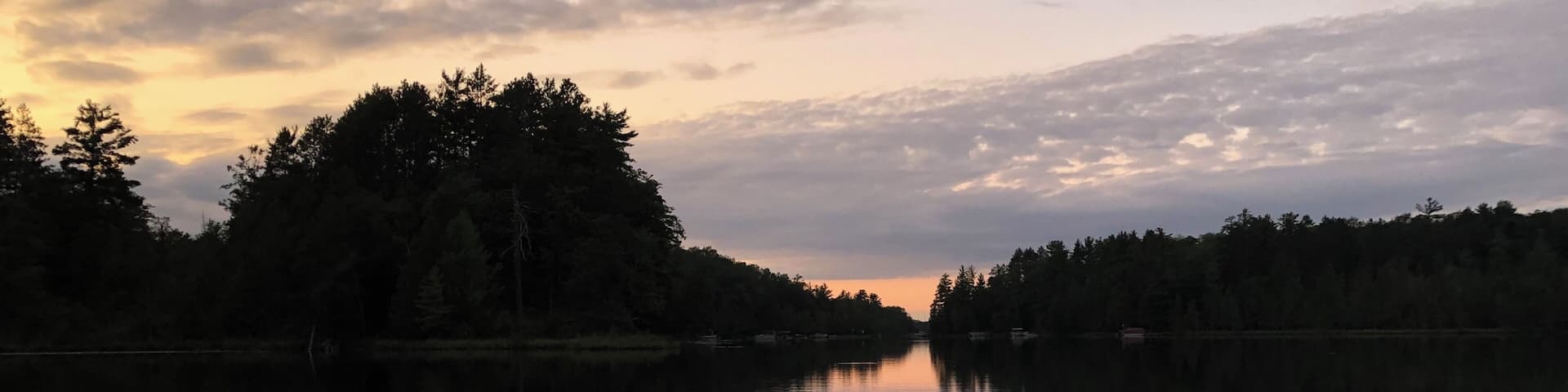 A calm lake at sunset with trees reflecting the sky.