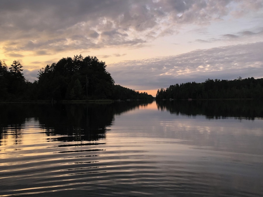 Un lac paisible au coucher du soleil, avec des arbres qui se reflètent dans le ciel.