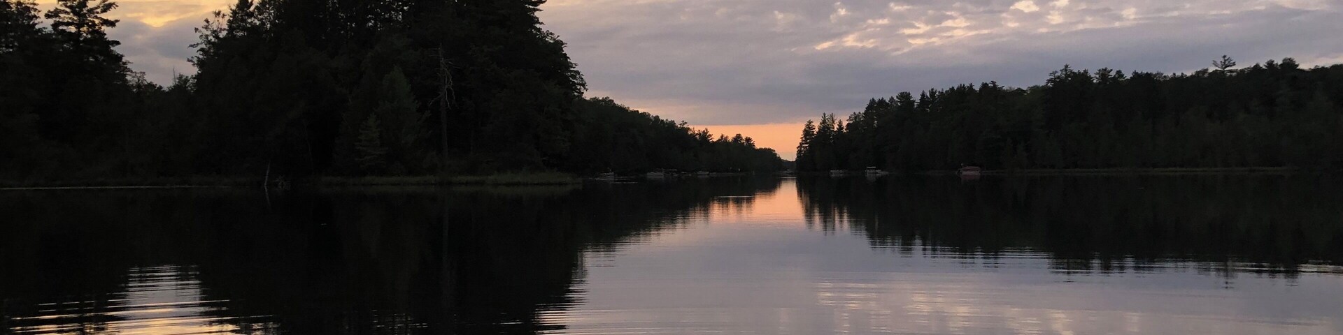 Un lago tranquilo al atardecer, con árboles que reflejan el cielo.