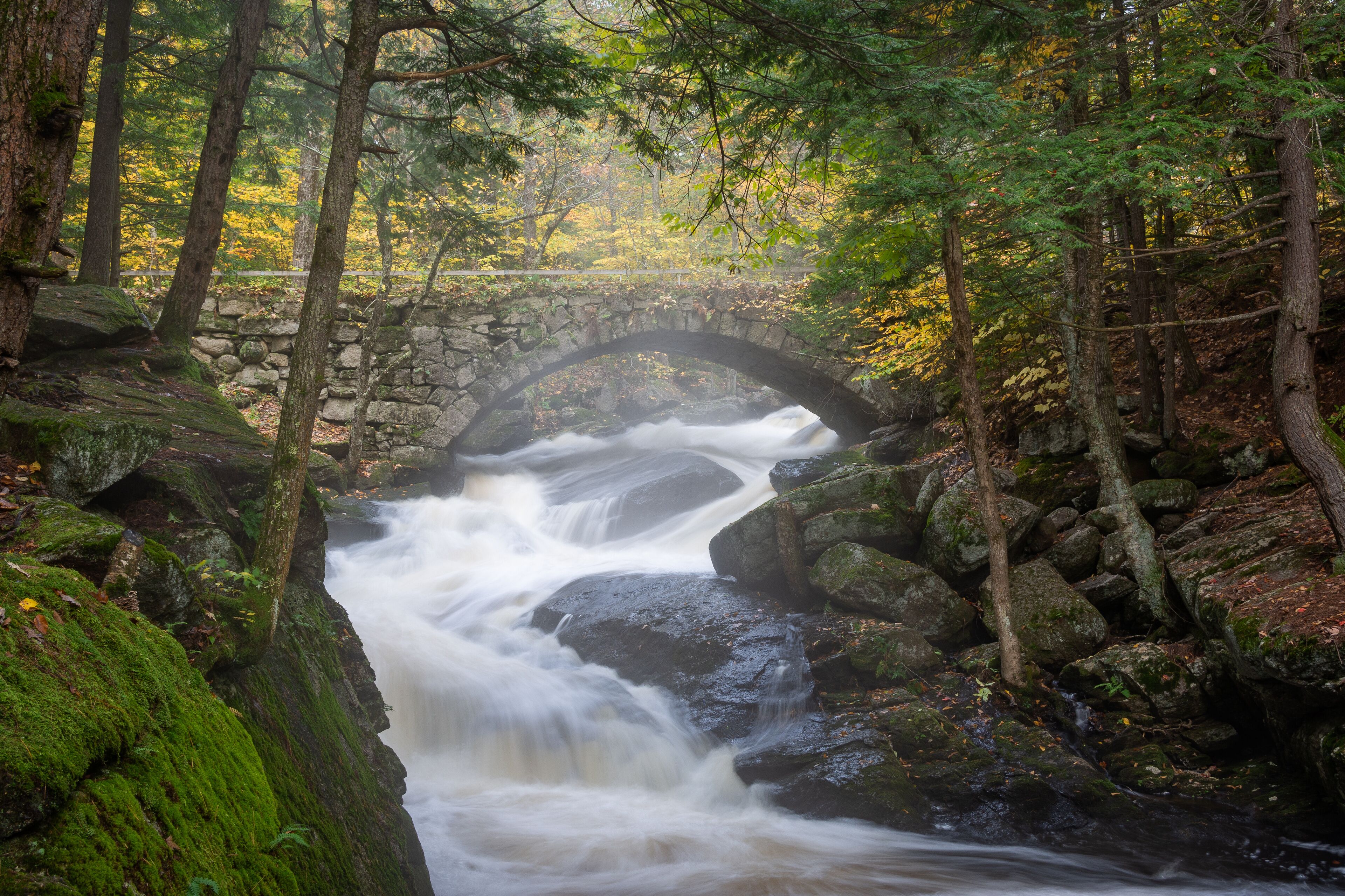 Stone arched bridge over waterfalls with fall foliage in Hillsborough, NH, New England  