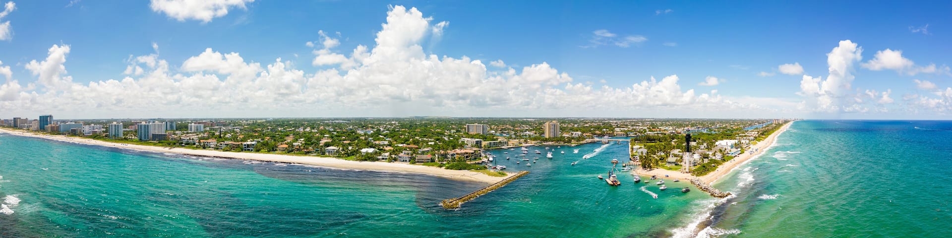 A coastal cityscape with a beach, marina, and dense urban area.