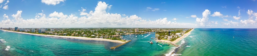 Un paisaje urbano costero con playa, puerto deportivo y zona urbana densa.