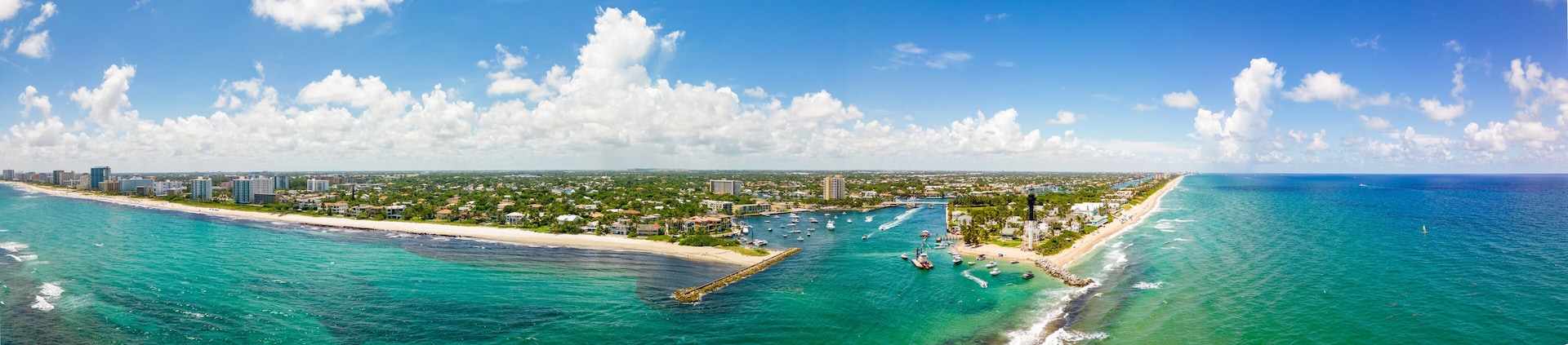 Un paisaje urbano costero con playa, puerto deportivo y zona urbana densa.