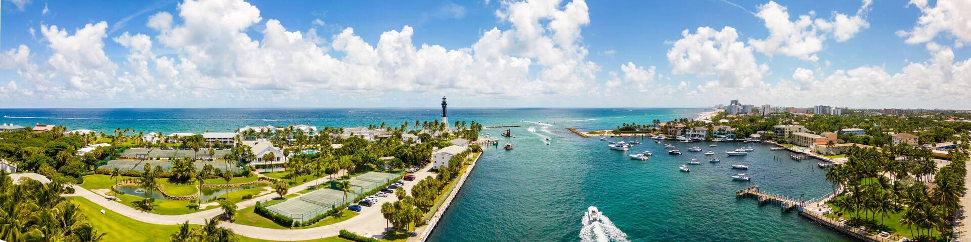 A coastal cityscape with a marina, golf course, and lighthouse.