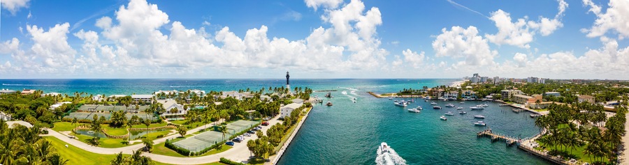 A coastal cityscape with a marina, golf course, and lighthouse.