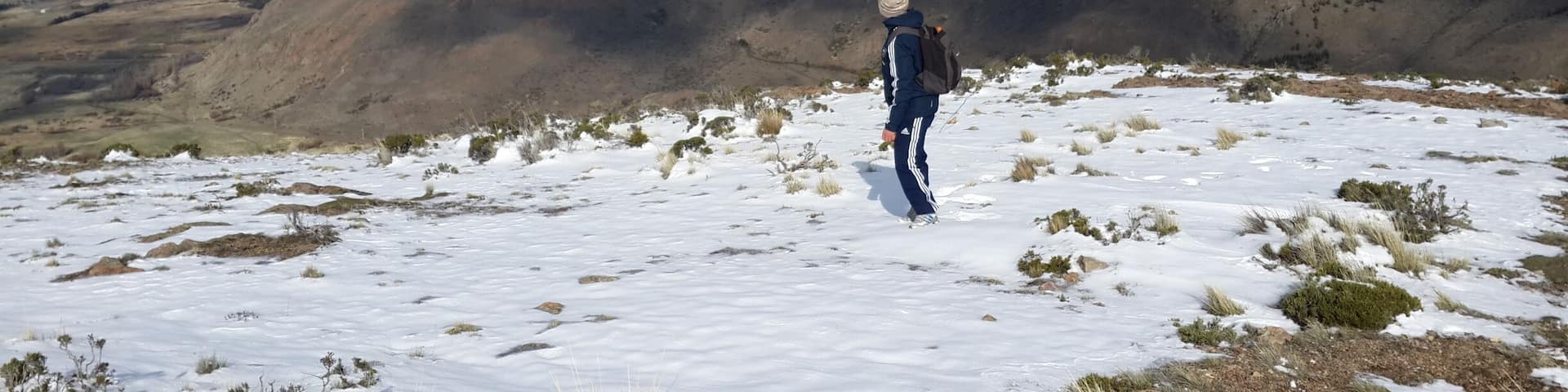 A person standing on a snowy mountain with a view of snow-covered peaks in the background.
