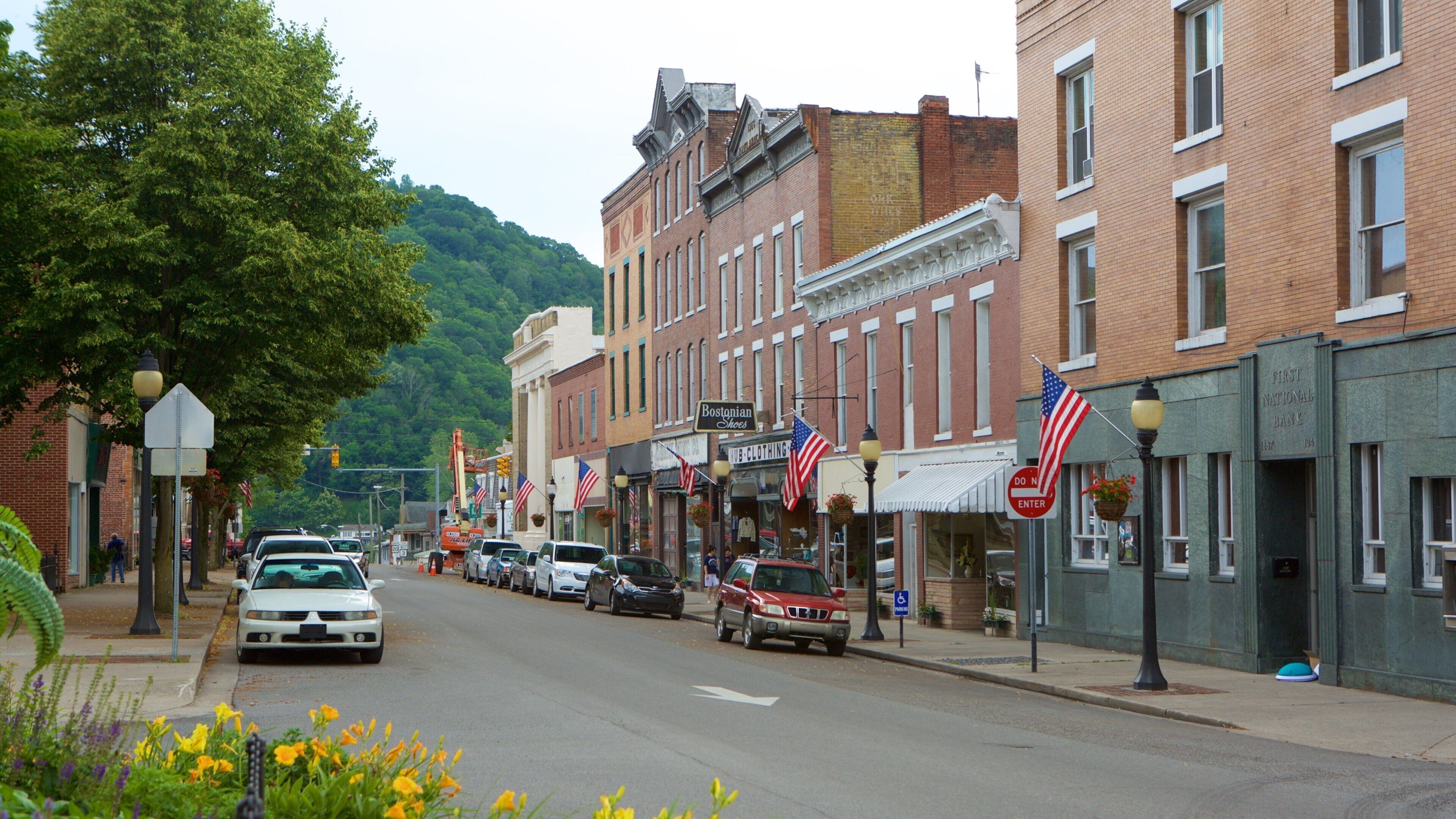 A street lined with historic buildings, American flags, and a First National Bank.