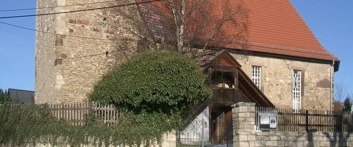 A church with a stone tower and a red-roofed building.