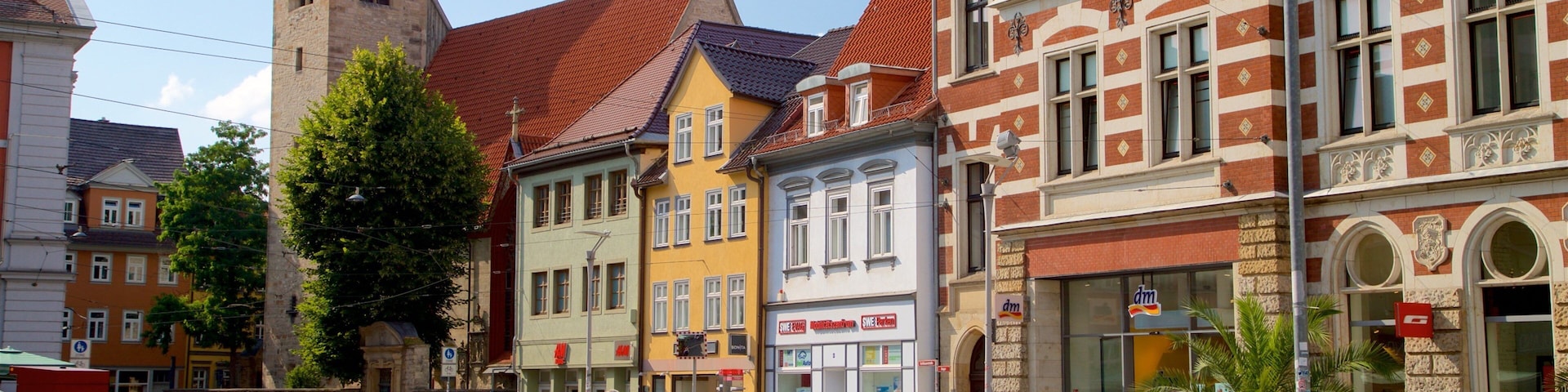 A bustling square with historic buildings, a church tower, and a row of shops.
