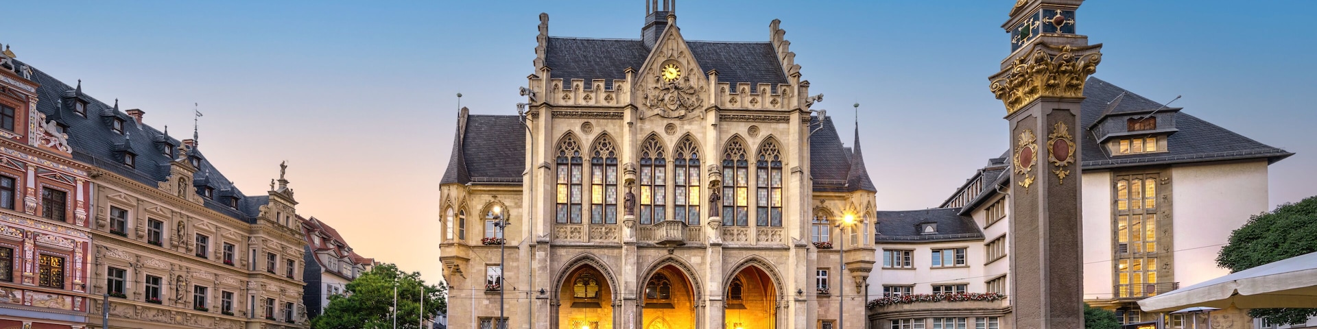 Un edificio histórico con una torre de reloj, una estatua y calles adoquinadas.