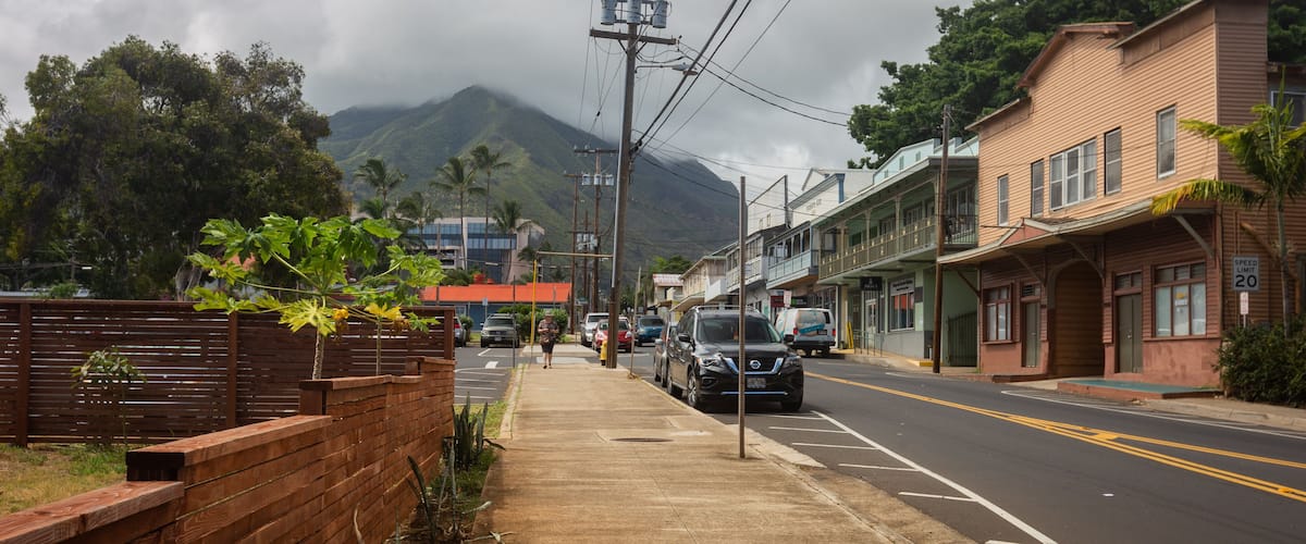 A street with buildings, a speed limit sign, and a mountain in the background.