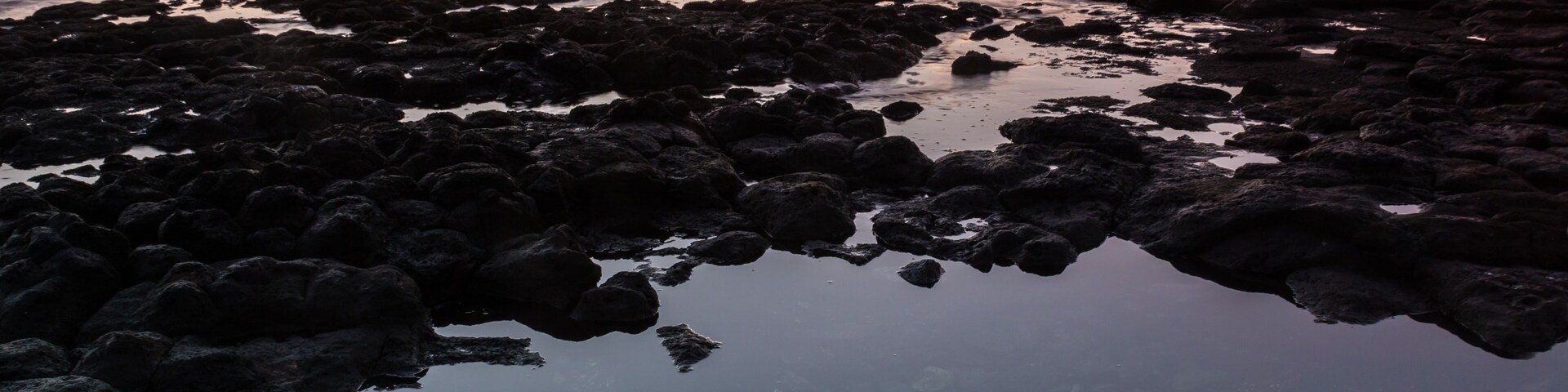 Una costa rocosa con aguas cristalinas que reflejan el atardecer.
