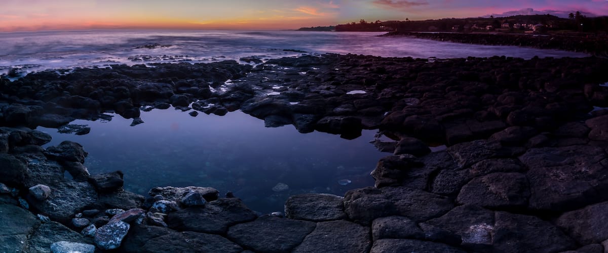 A rocky shoreline with a calm body of water reflecting the sky.