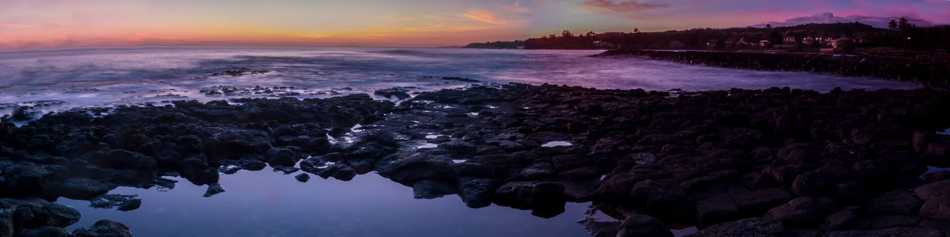A rocky shoreline with a calm body of water reflecting the sky.