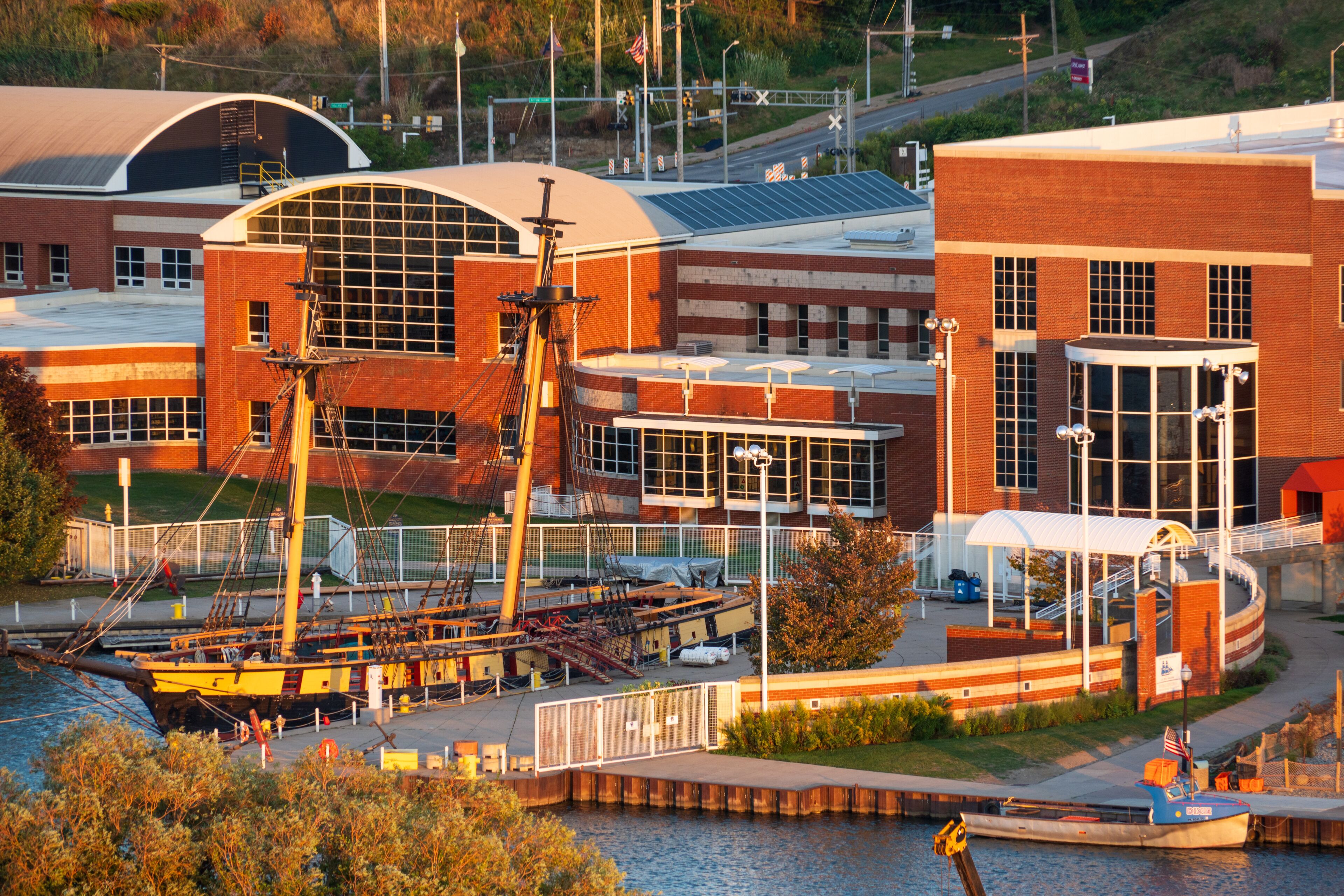 A waterfront with a large building featuring a curved roof and a smaller brick structure.