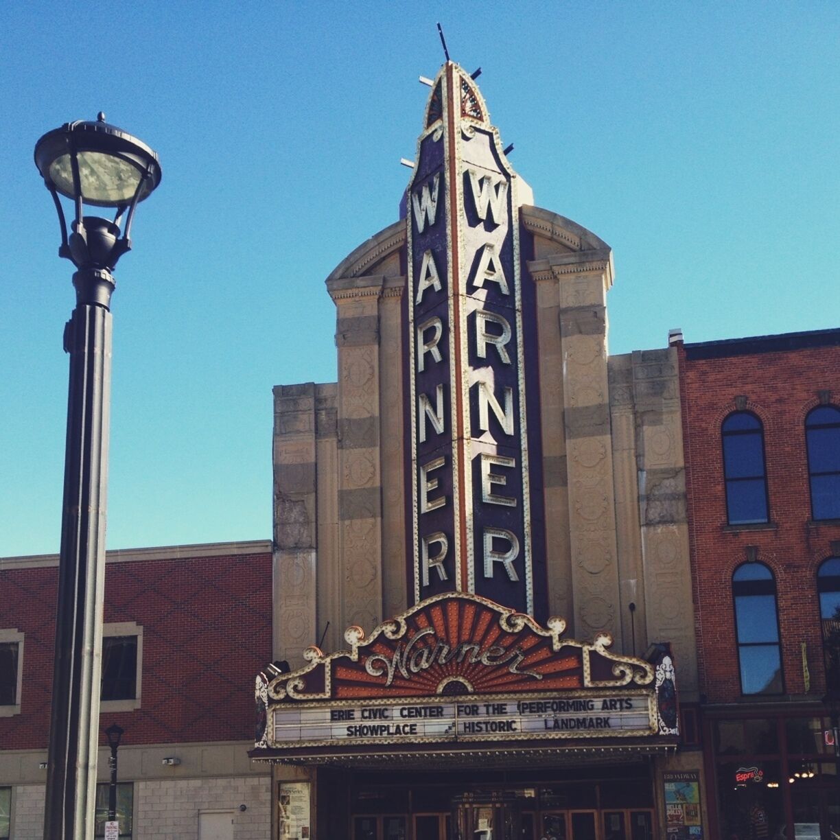 The Warner theater with a classic marquee and a tall clock tower.