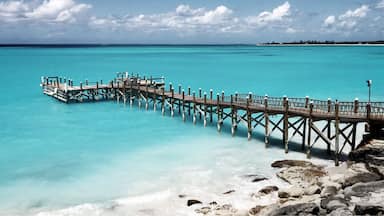 A wooden pier extending into turquoise waters with a rocky shoreline in the foreground.