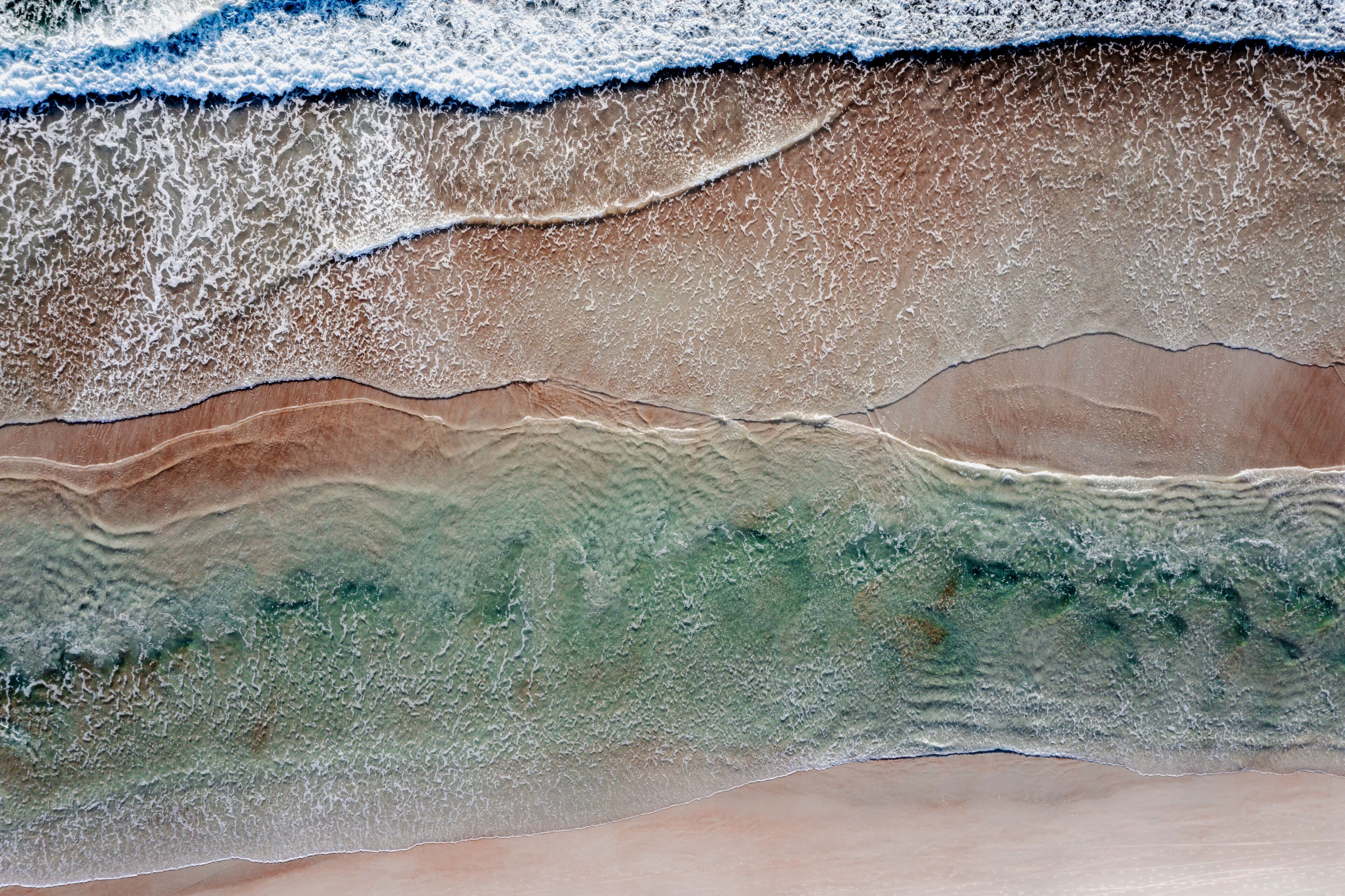 A beach with waves, sand, and a visible underwater layer.