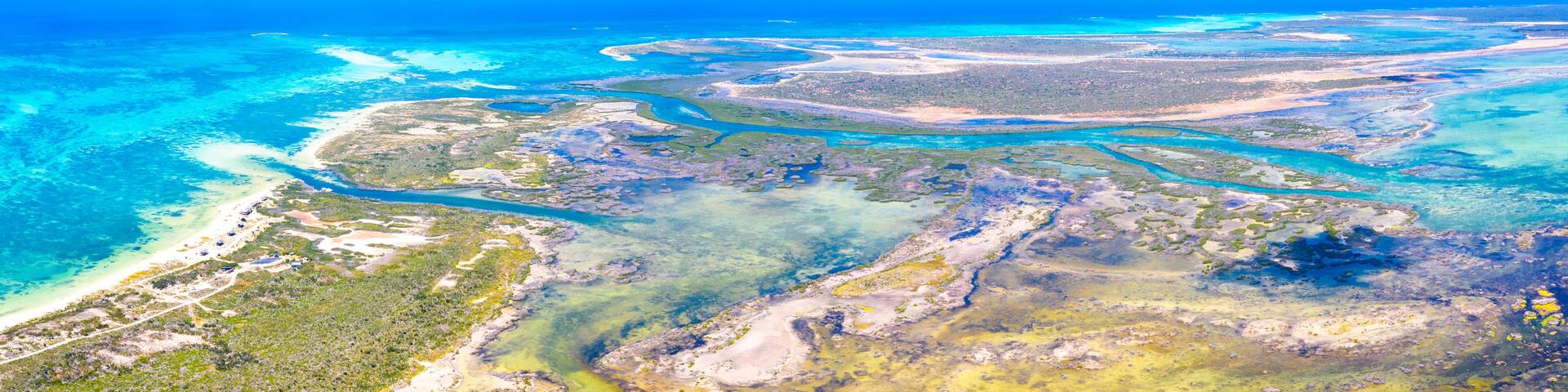 A coastal landscape with clear blue waters, sandy beaches, and a network of waterways.