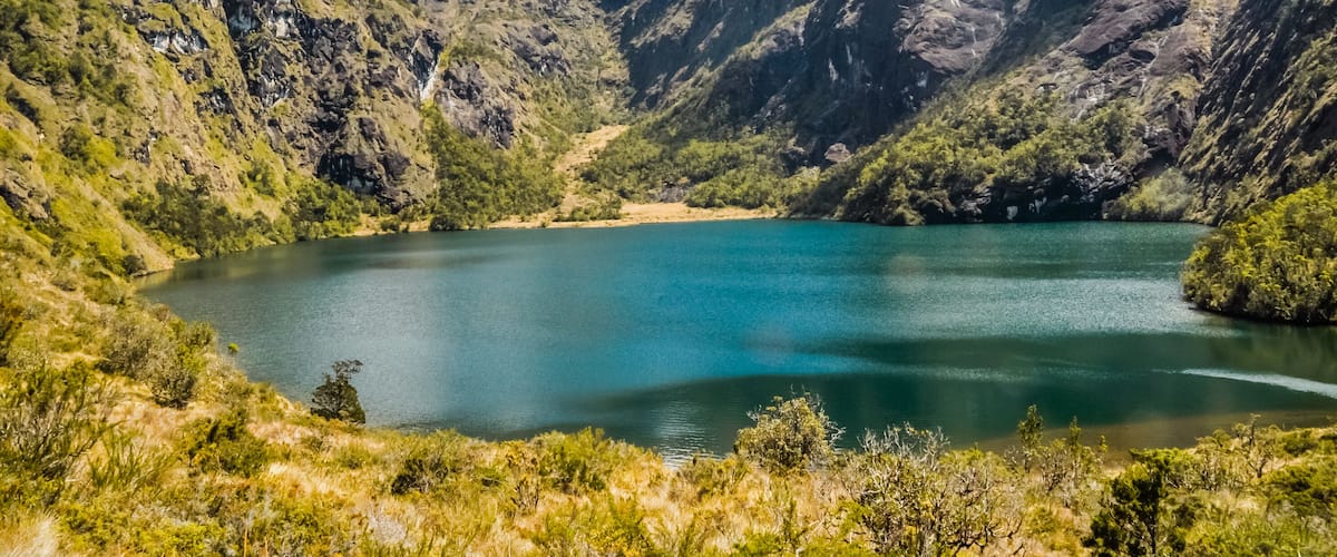 A lake surrounded by rugged mountains with lush greenery.