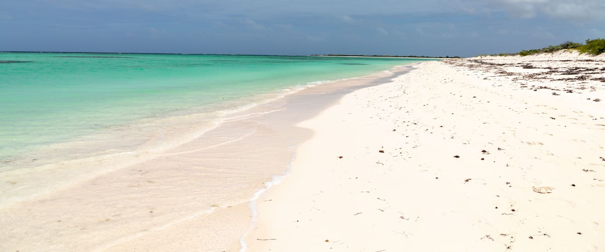 A beach with clear turquoise water and white sand.