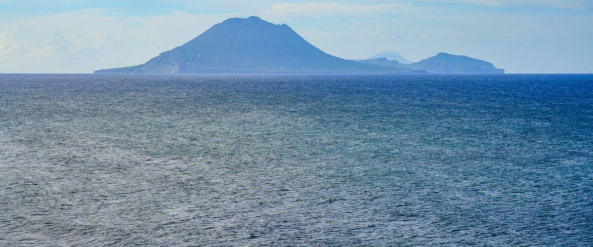 A calm sea with a mountain in the distance.