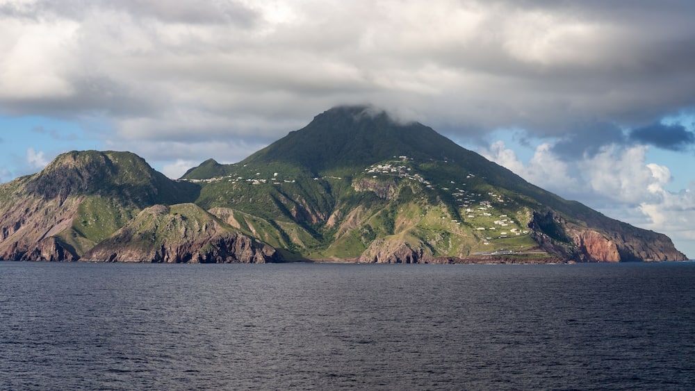 Une île montagneuse aux côtes escarpées, parsemée de bâtiments.