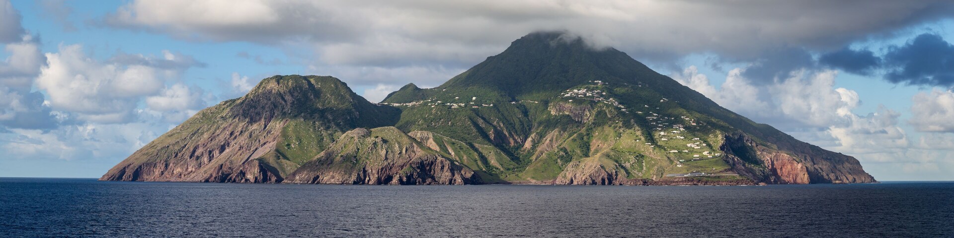 Una isla montañosa con una costa escarpada y edificios dispersos.