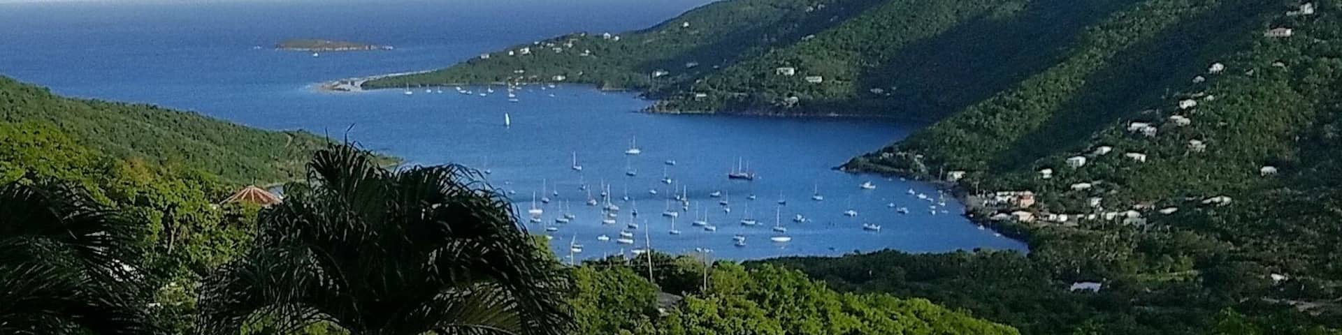 A pool overlooking a bay with boats and a hilly landscape.
