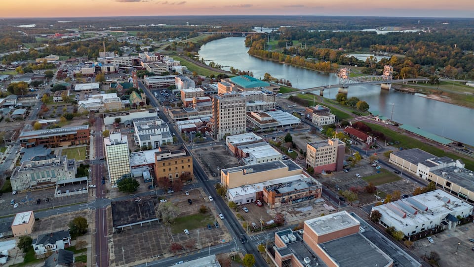 An aerial view of a city with a river, industrial buildings, and a bridge.