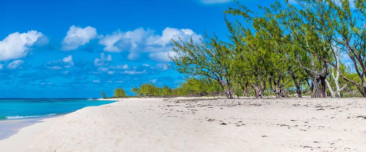 A beach with white sand and turquoise water.