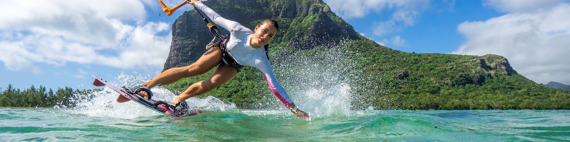 Beautiful girl with black hair kiting in the clear waters of the Indian Ocean on the background of clouds and high mountains.; Shutterstock ID 394987096