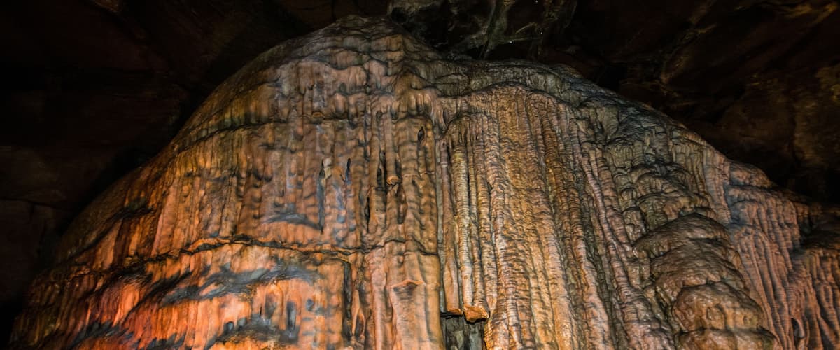 A large, illuminated cave formation with intricate textures and patterns.