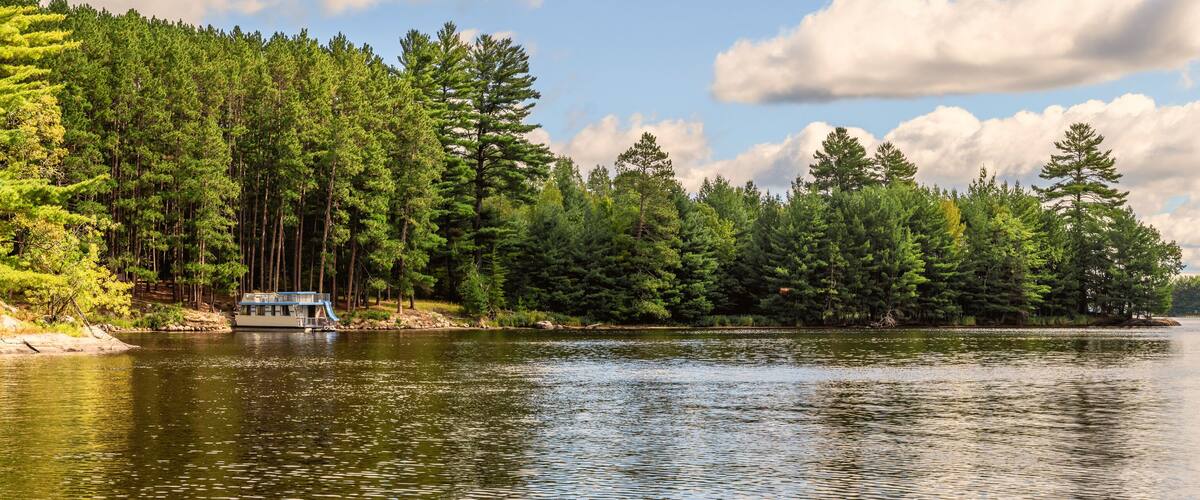 A calm lake surrounded by dense forest and a dock.