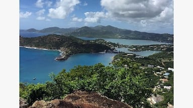 Un paisaje costero con cielo despejado, una bahía y montañas a lo lejos.