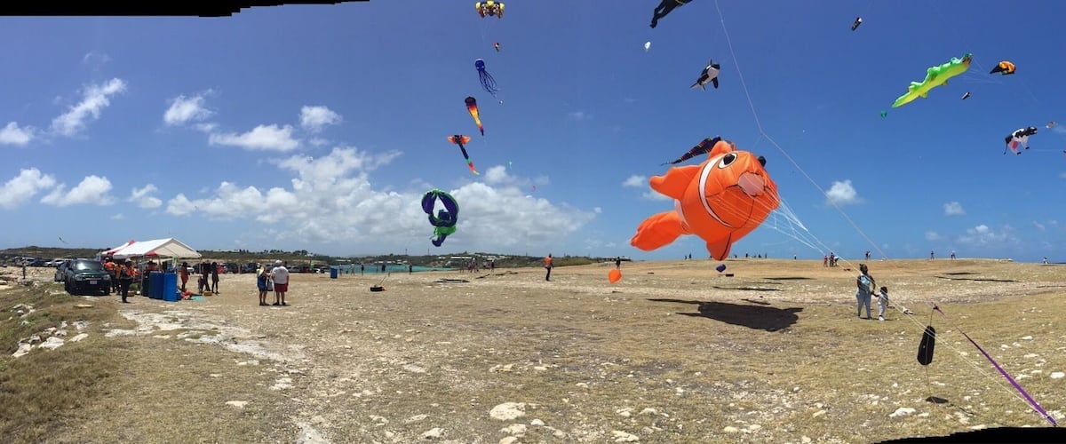 A beach with numerous colorful kites flying in the sky.