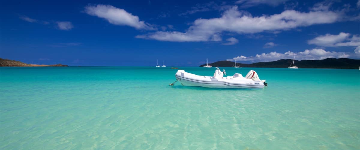 A clear turquoise sea with a white boat anchored in the middle.