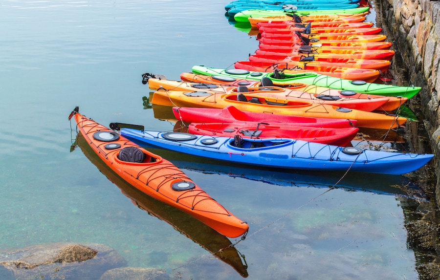 a row of colorful fiberglass kayaks for rent in a small Massachusetts harbor